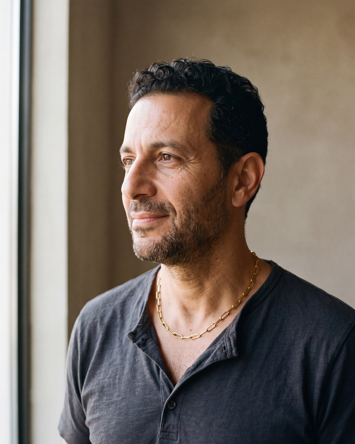 Man in a charcoal henley seen in profile wearing the gold-tone Atlas flat link chain