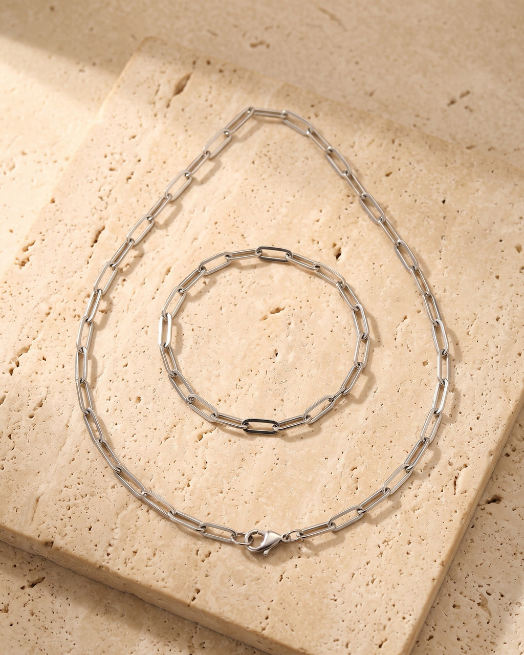 The whole silver-tone Atlas flat link chain laid on warm stone