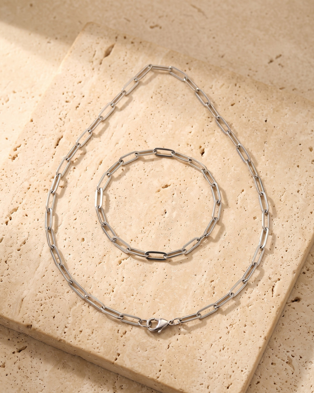 The whole silver-tone Atlas flat link chain laid on warm stone