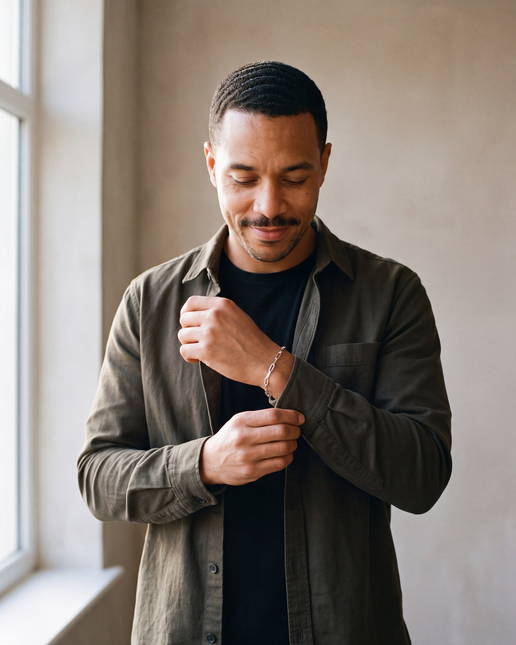 Man in an olive overshirt adjusting his sleeve wearing the silver-tone Atlas flat link chain