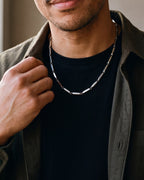 Close-up of the silver-tone Atlas geometric bar link chain worn by a man, shown at true size