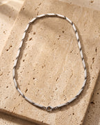 The whole silver-tone Atlas geometric bar link chain laid on warm stone