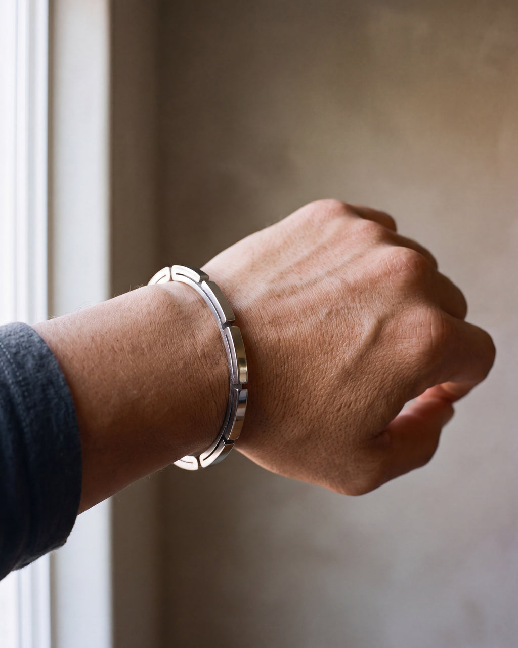 Close-up of the silver-tone Atlas geometric cuff bracelet worn by a man, shown at true size