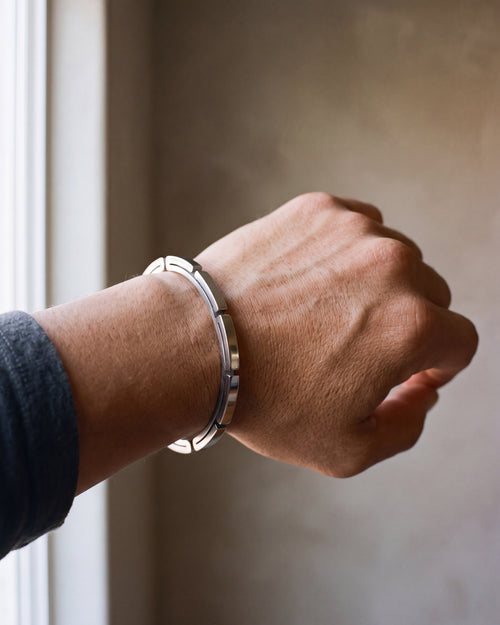 Close-up of the silver-tone Atlas geometric cuff bracelet worn by a man, shown at true size