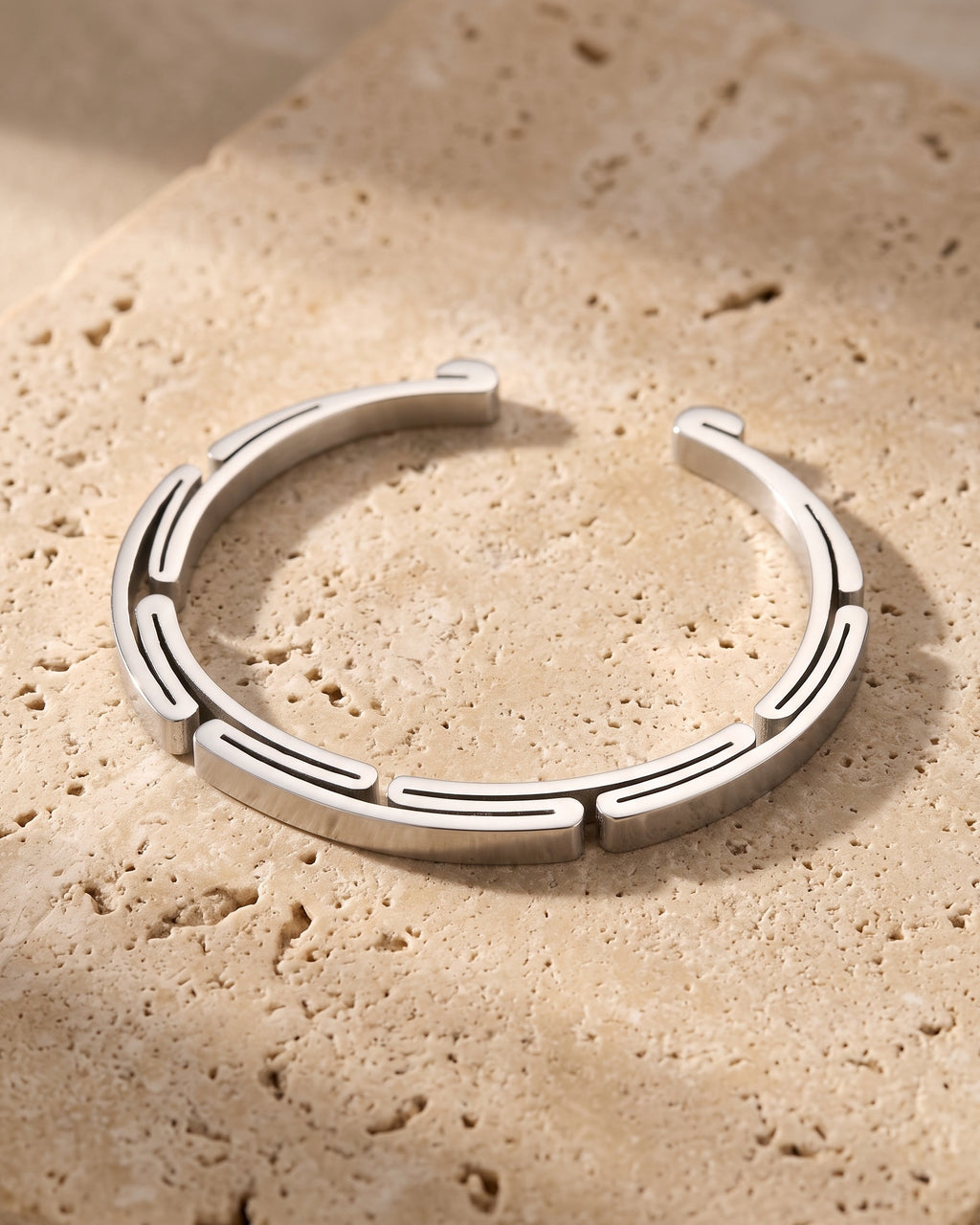 The whole silver-tone Atlas geometric cuff bracelet laid on warm stone