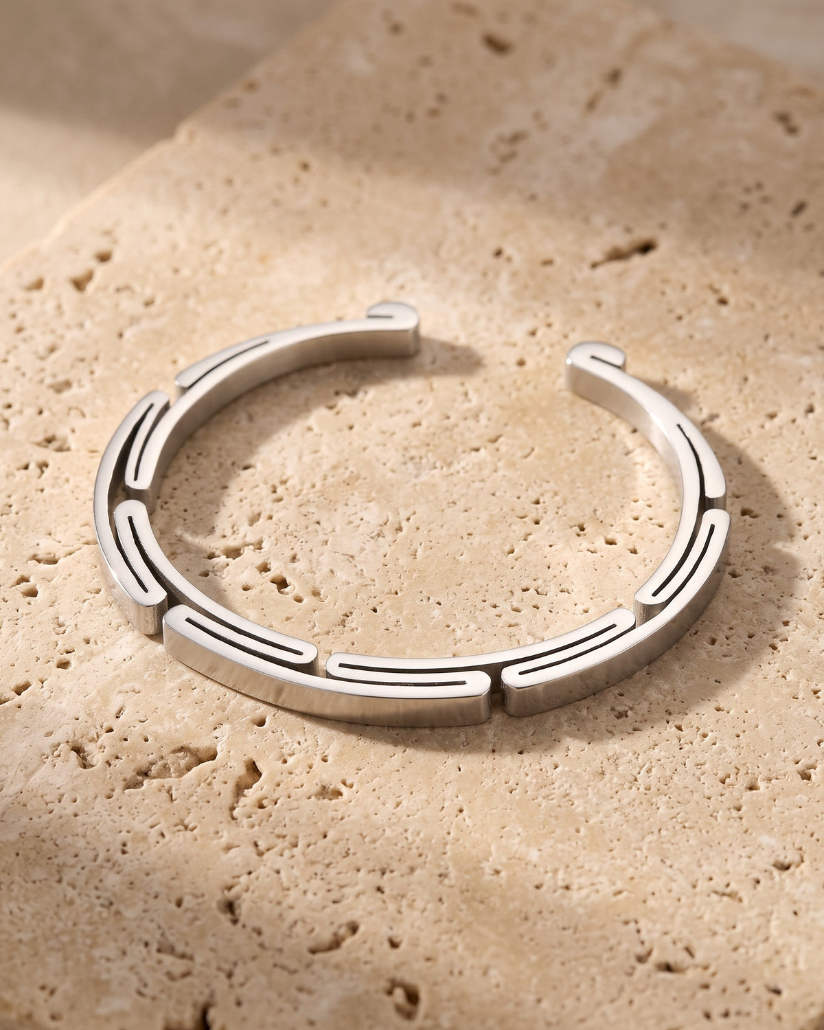 The whole silver-tone Atlas geometric cuff bracelet laid on warm stone