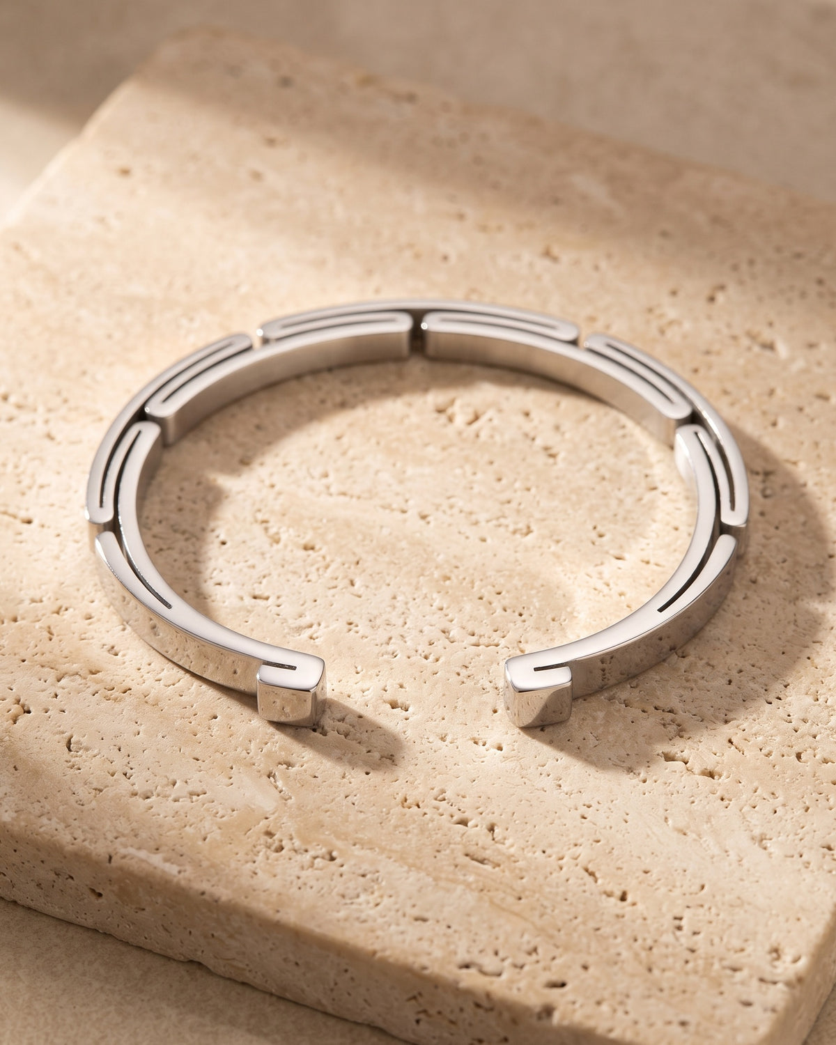 The silver-tone Atlas geometric link cuff on warm stone