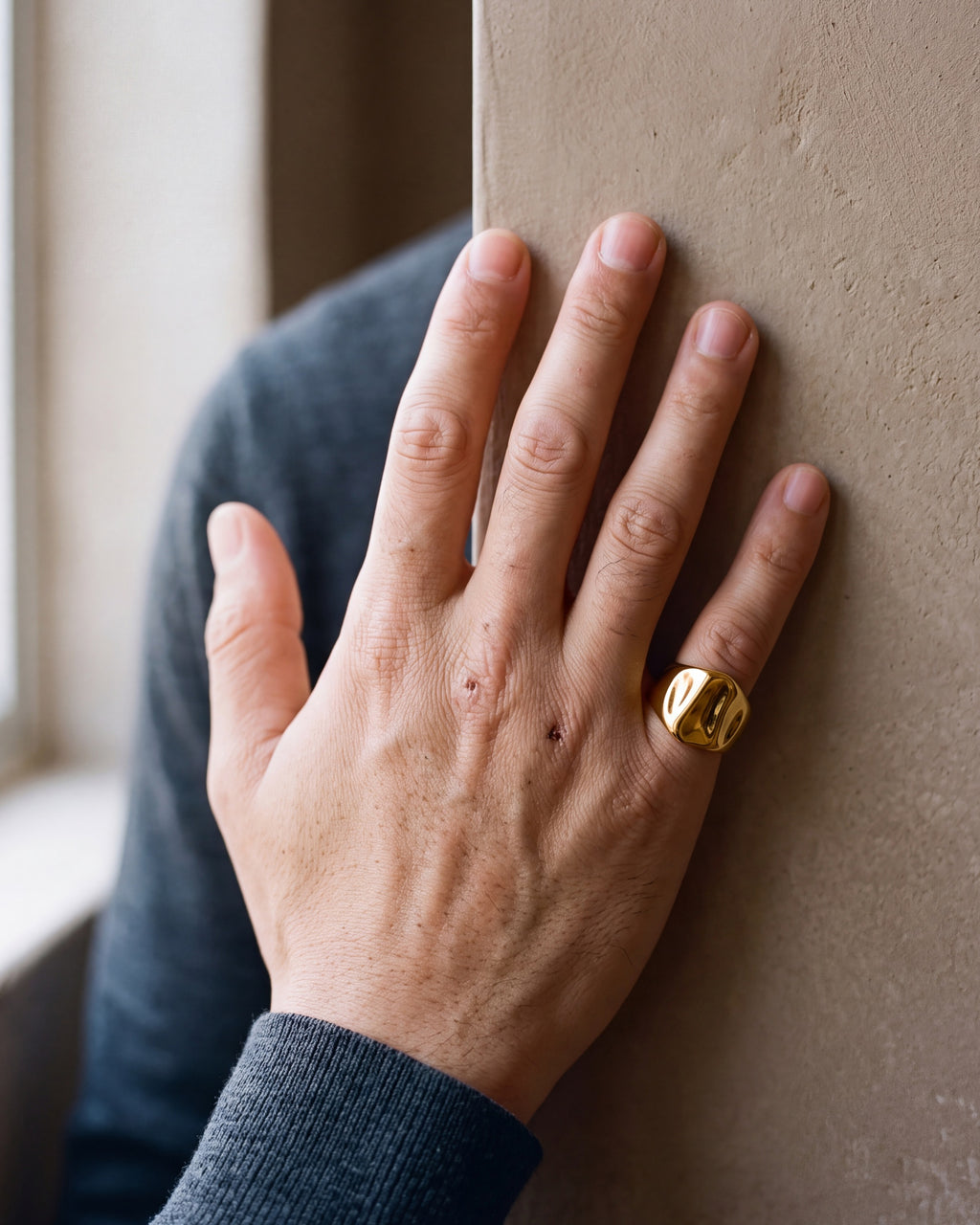 Close-up of the Atlas gold-tone hammered signet ring on a man's little finger
