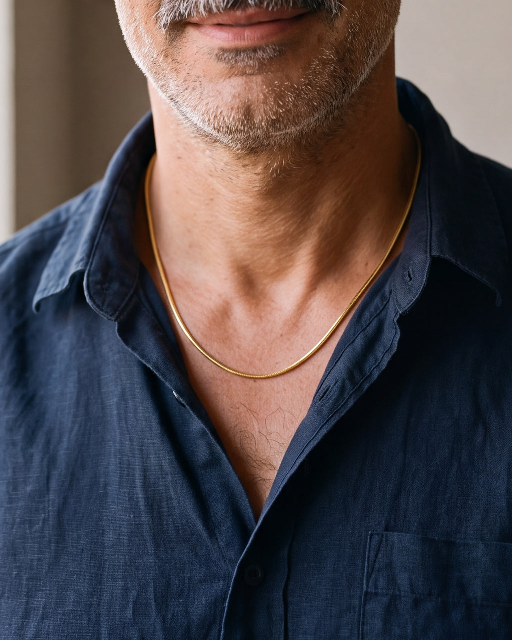 Close-up of the Atlas gold-tone snake chain worn at the base of the neck