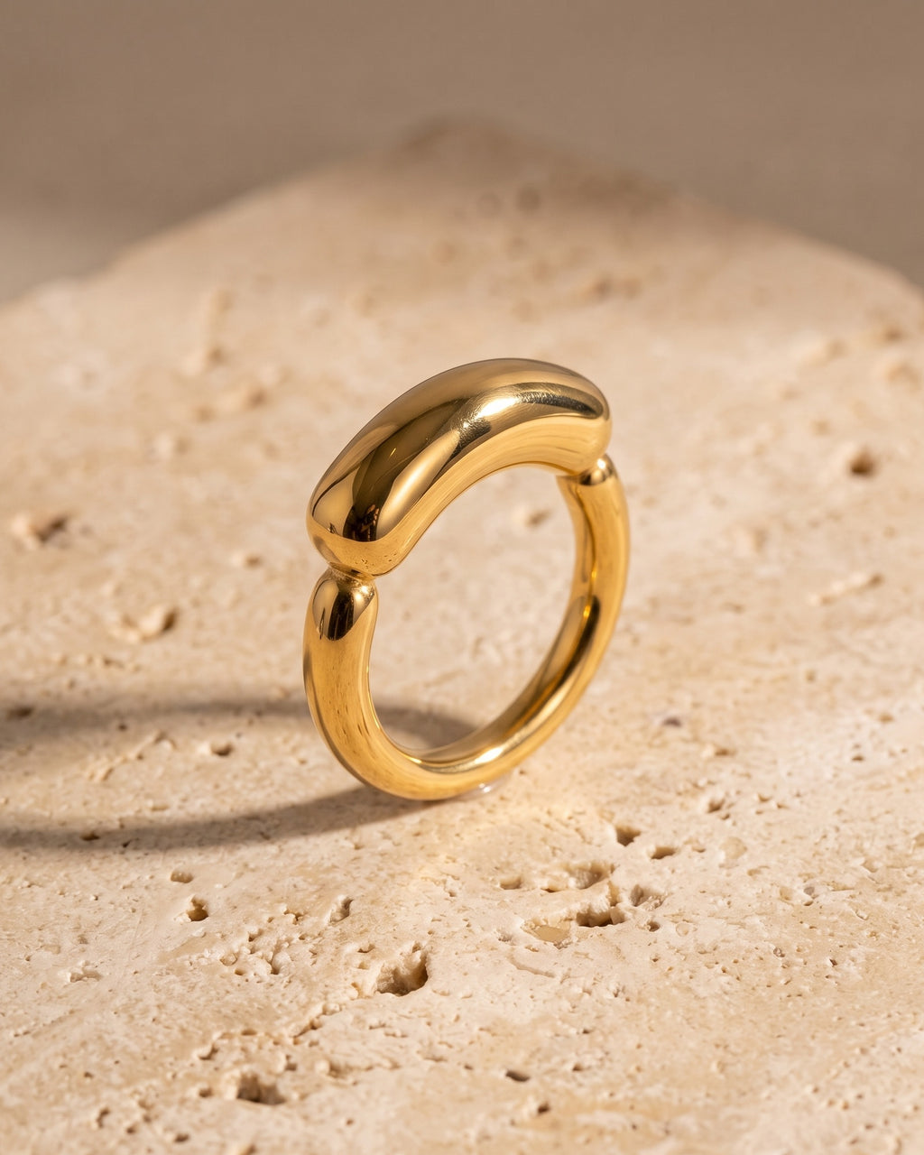 The whole gold-tone Atlas Gold-Tone Tapered Dome Ring lying on warm travertine stone