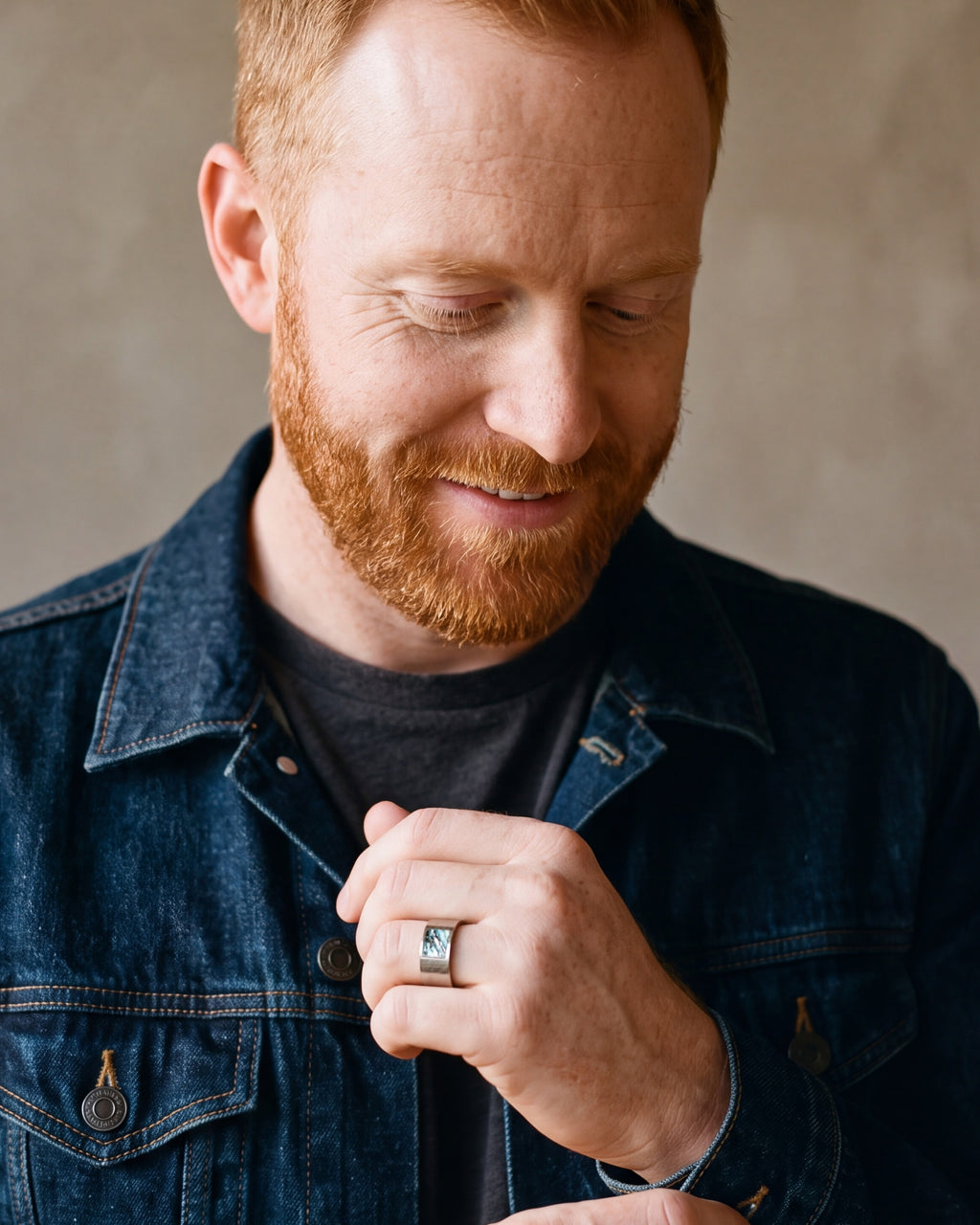 Man in a denim jacket adjusting his cuff, wearing the silver Atlas hammered abalone inlay ring