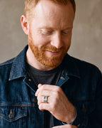 Man in a denim jacket adjusting his cuff, wearing the silver Atlas hammered abalone inlay ring