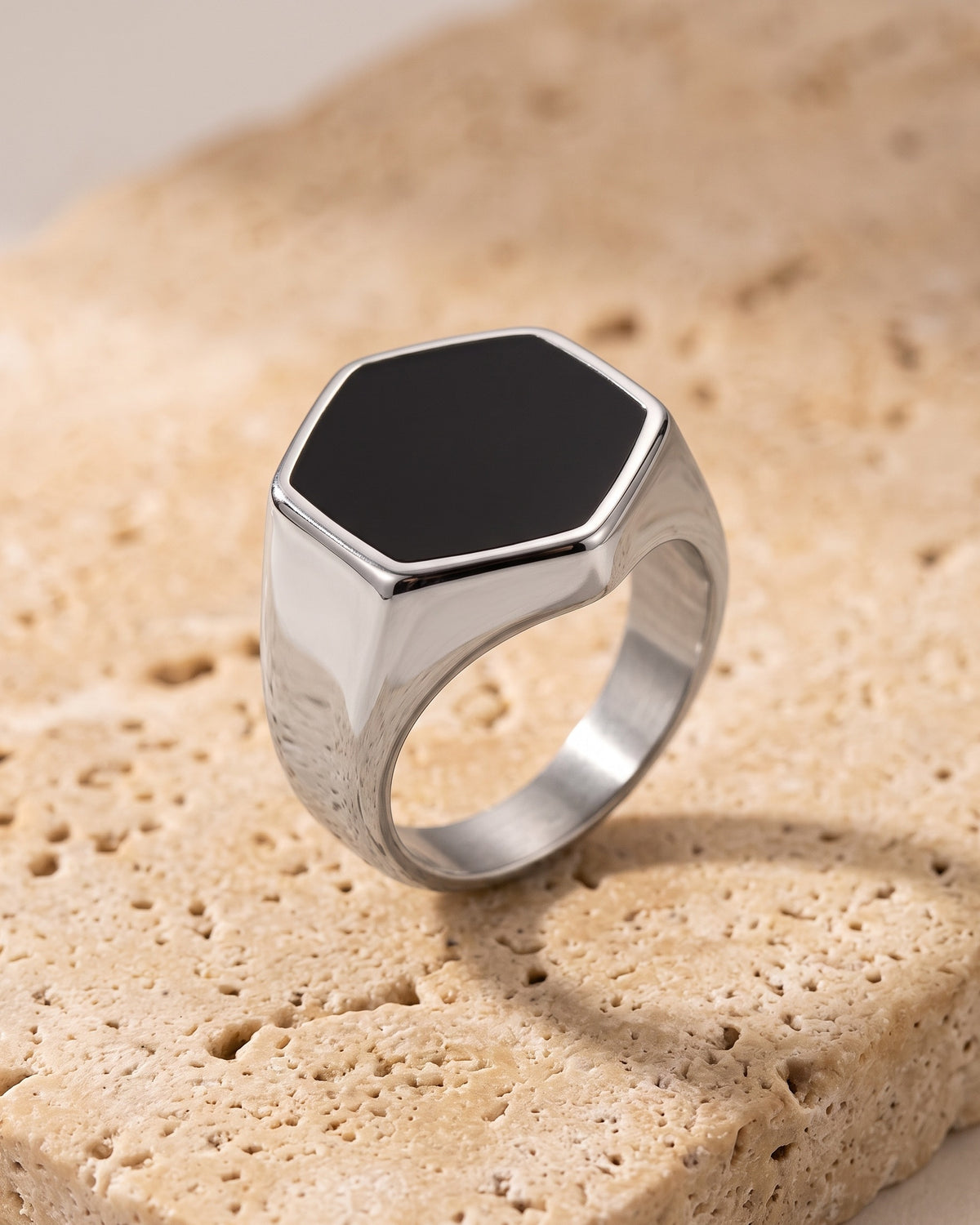 The whole silver Atlas hexagon signet ring laid on warm stone