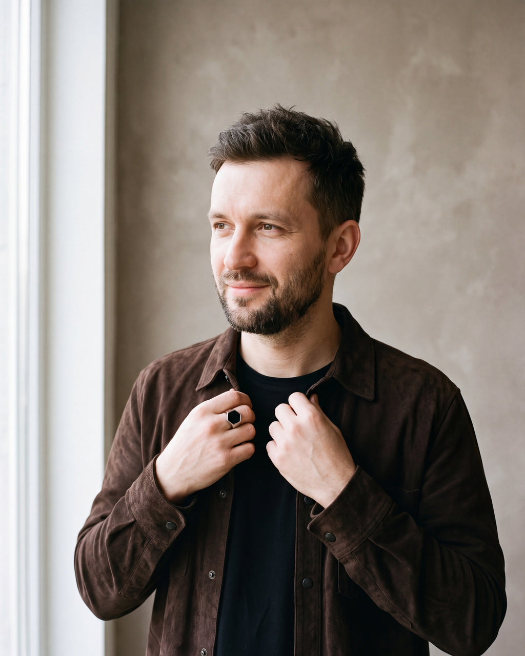 Man in a brown suede overshirt by a window wearing the silver Atlas hexagon signet ring