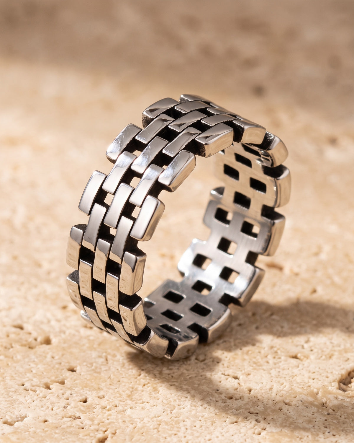 The whole silver-tone Atlas Hollow Link Ring lying on warm travertine stone