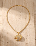 The whole gold-tone Atlas iced leopard pendant necklace laid on warm stone
