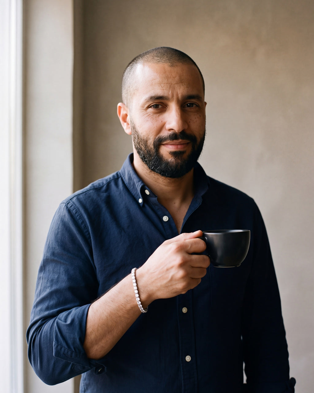 Man in a navy oxford shirt holding a coffee cup wearing the silver Atlas iced tennis bracelet