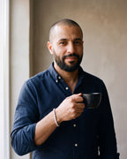 Man in a navy oxford shirt holding a coffee cup wearing the silver Atlas iced tennis bracelet