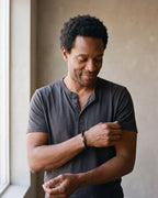 Man in a dark navy linen shirt wearing the Atlas iced X bracelet in braided leather in gold-tone steel