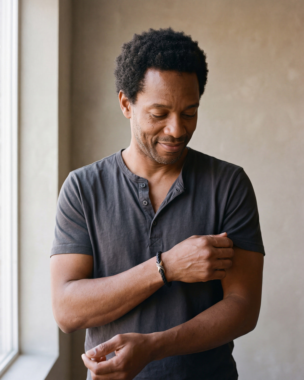 Man in a dark navy linen shirt wearing the Atlas iced X bracelet in braided leather in gold-tone steel