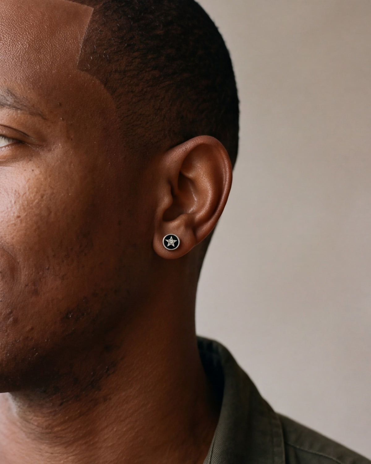 Close-up of the Atlas star inlay barbell stud on a man's earlobe [c:silverstar]