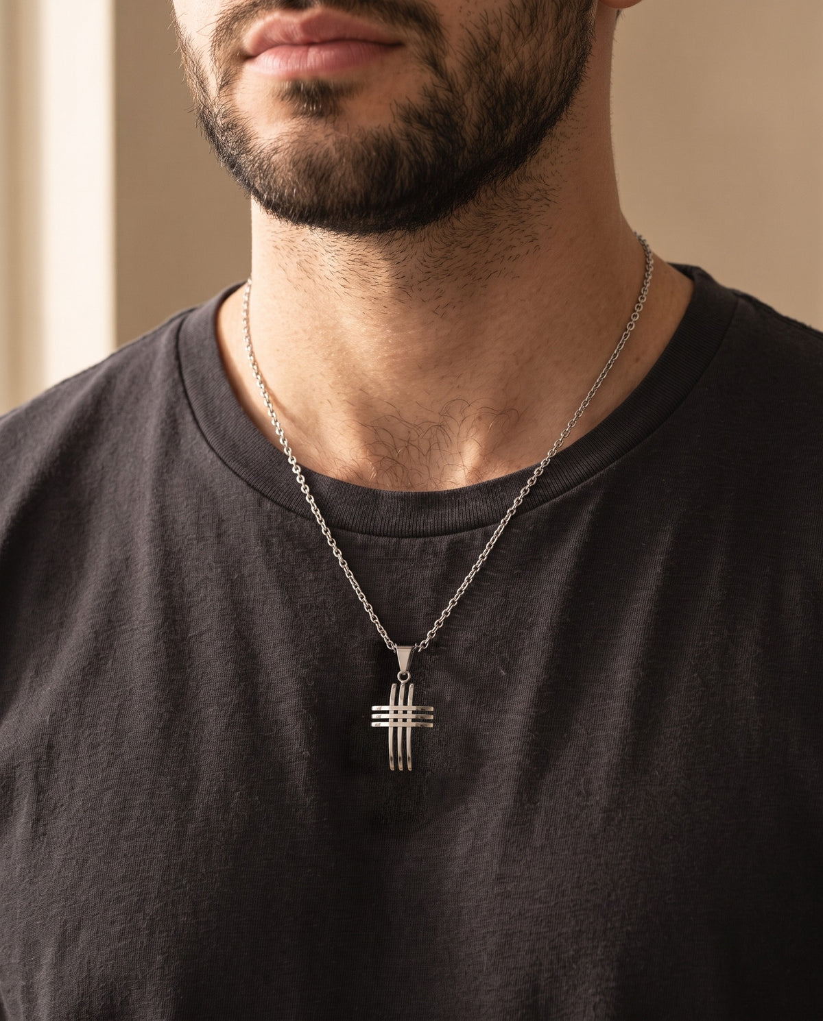 Close-up of the silver-tone Atlas interlocking cross pendant necklace worn on a dark t-shirt, true size