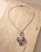 The whole silver-tone Atlas Interlocking Cross Pendant Necklace lying on warm travertine stone