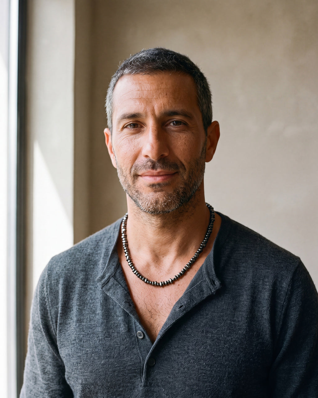 Second man in a fine-gauge charcoal-grey merino knit with a henley neckline wearing the black Atlas irregular bead chain