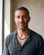 Second man in a fine-gauge charcoal-grey merino knit with a henley neckline wearing the black Atlas irregular bead chain