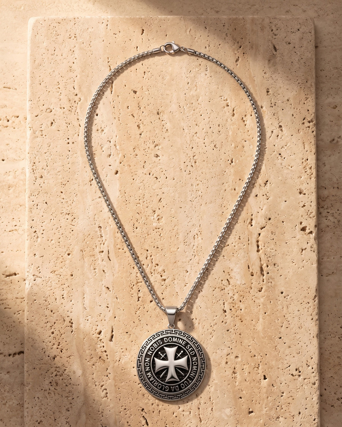 The silver Atlas Knights Templar Cross Necklace laid on warm travertine stone [c:silvernostones]