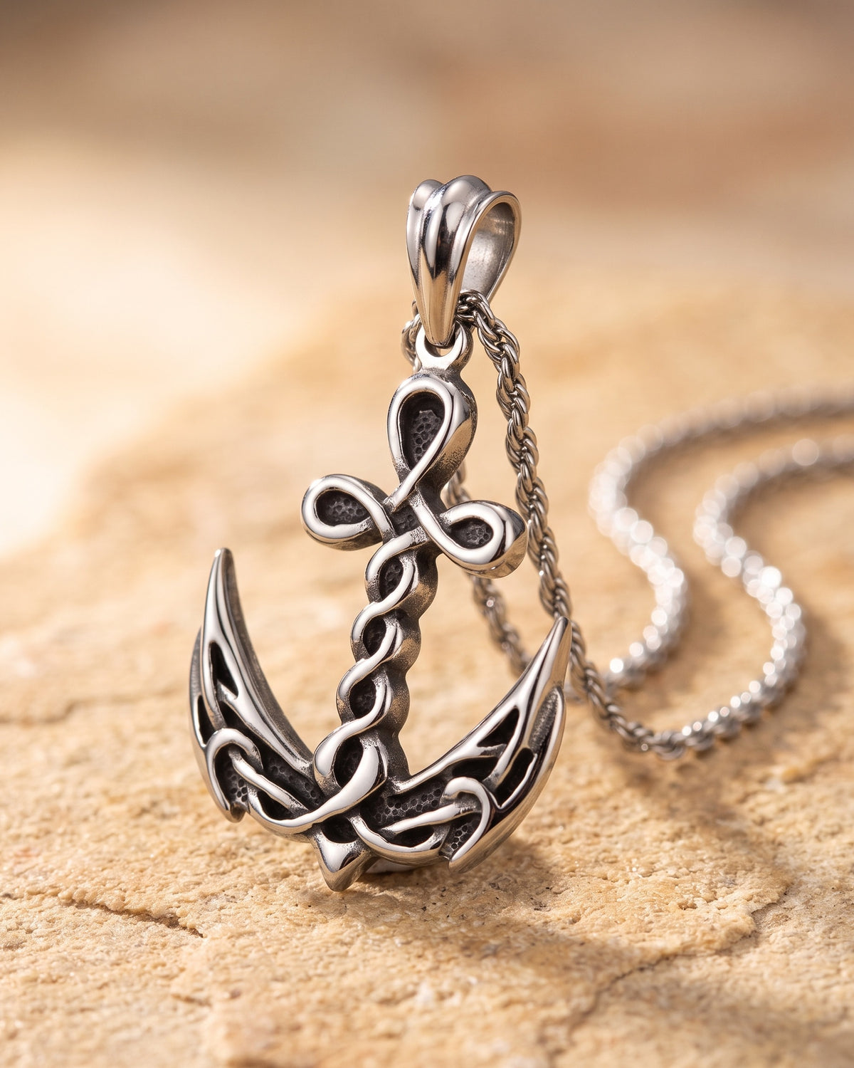 Close-up of the silver-tone Atlas knotwork anchor pendant resting on warm stone