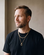 Man in a heavyweight black cotton crew-neck t-shirt wearing the black Atlas Layered Figaro Chain Necklace with Black Stone