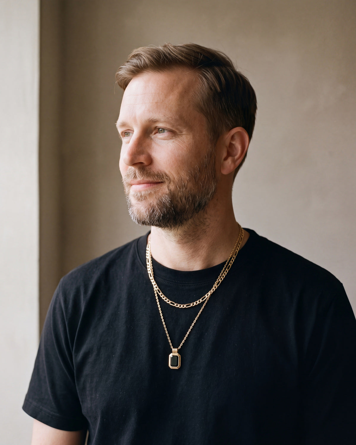 Man in a heavyweight black cotton crew-neck t-shirt wearing the black Atlas Layered Figaro Chain Necklace with Black Stone