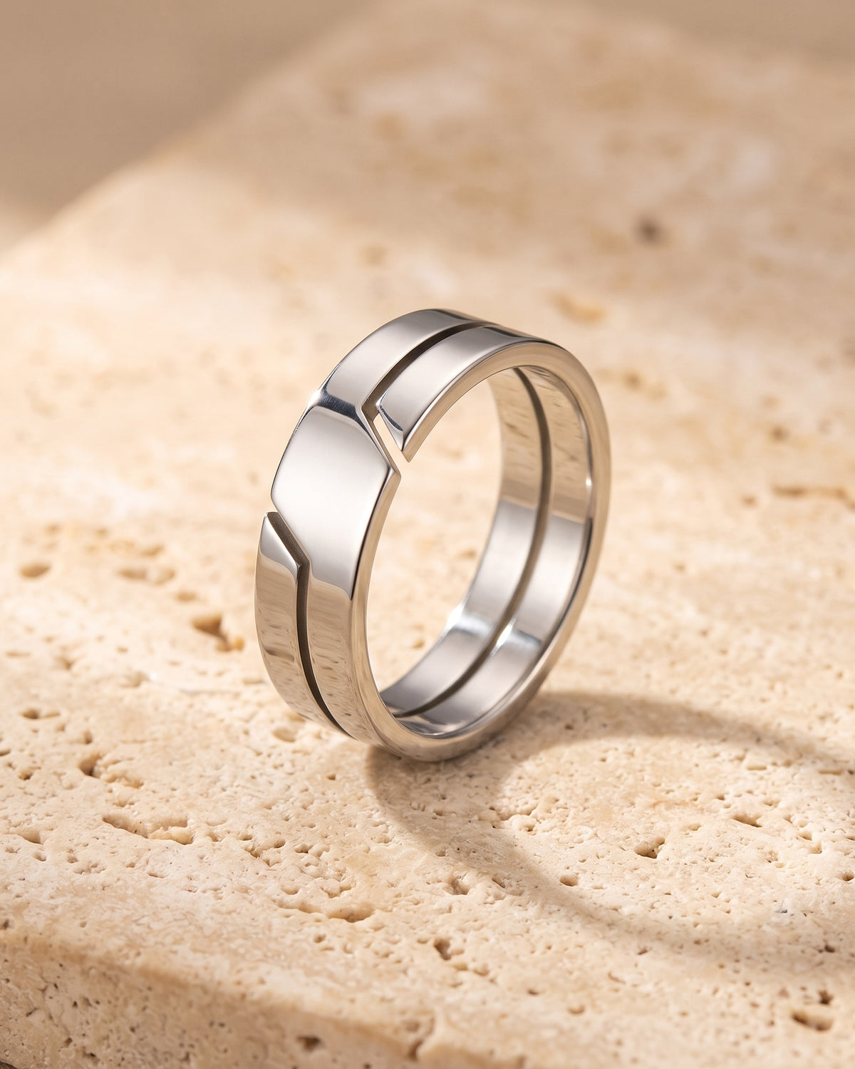 The whole silver Atlas layered split band ring lying on warm travertine stone