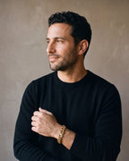 Man in a black merino crew-neck sweater wearing the gold-tone Atlas Miami Cuban Bracelet