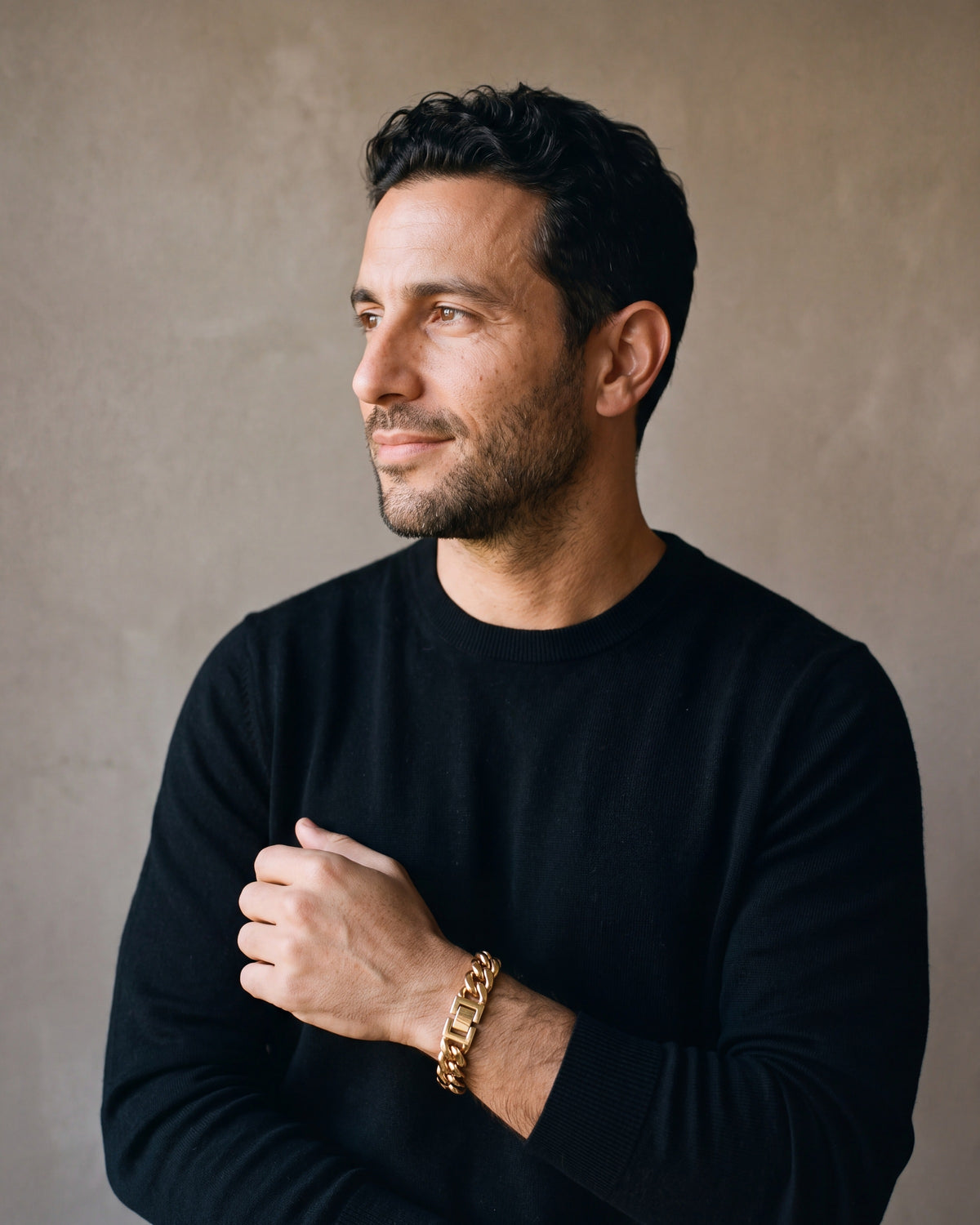 Man in a black merino crew-neck sweater wearing the gold-tone Atlas Miami Cuban Bracelet