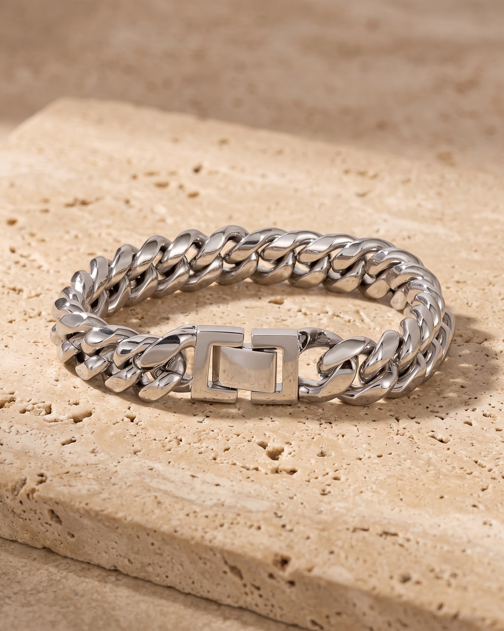 The whole silver-tone Atlas Miami Cuban Bracelet lying on warm travertine stone