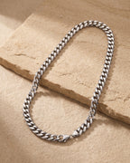 The whole silver Atlas Miami Cuban chain laid on warm stone, lobster clasp closed