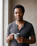 Man in a charcoal henley wearing the Atlas minimal cross pendant necklace in gold-tone steel