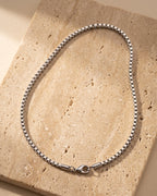 The whole silver Atlas minimalist box chain lying on warm travertine stone