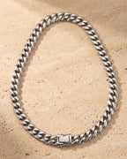 The whole silver Atlas mirror-polished Cuban chain on warm stone, box clasp closed