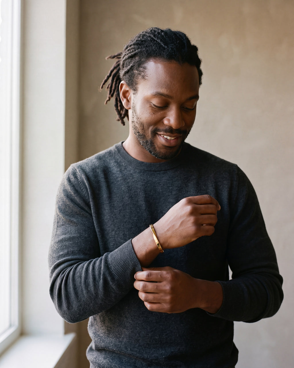 Second man in a charcoal fine-gauge knit crew-neck sweater wearing the gold-tone Atlas mobius twist cuff bracelet