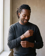 Second man in a charcoal fine-gauge knit crew-neck sweater wearing the gold-tone Atlas mobius twist cuff bracelet