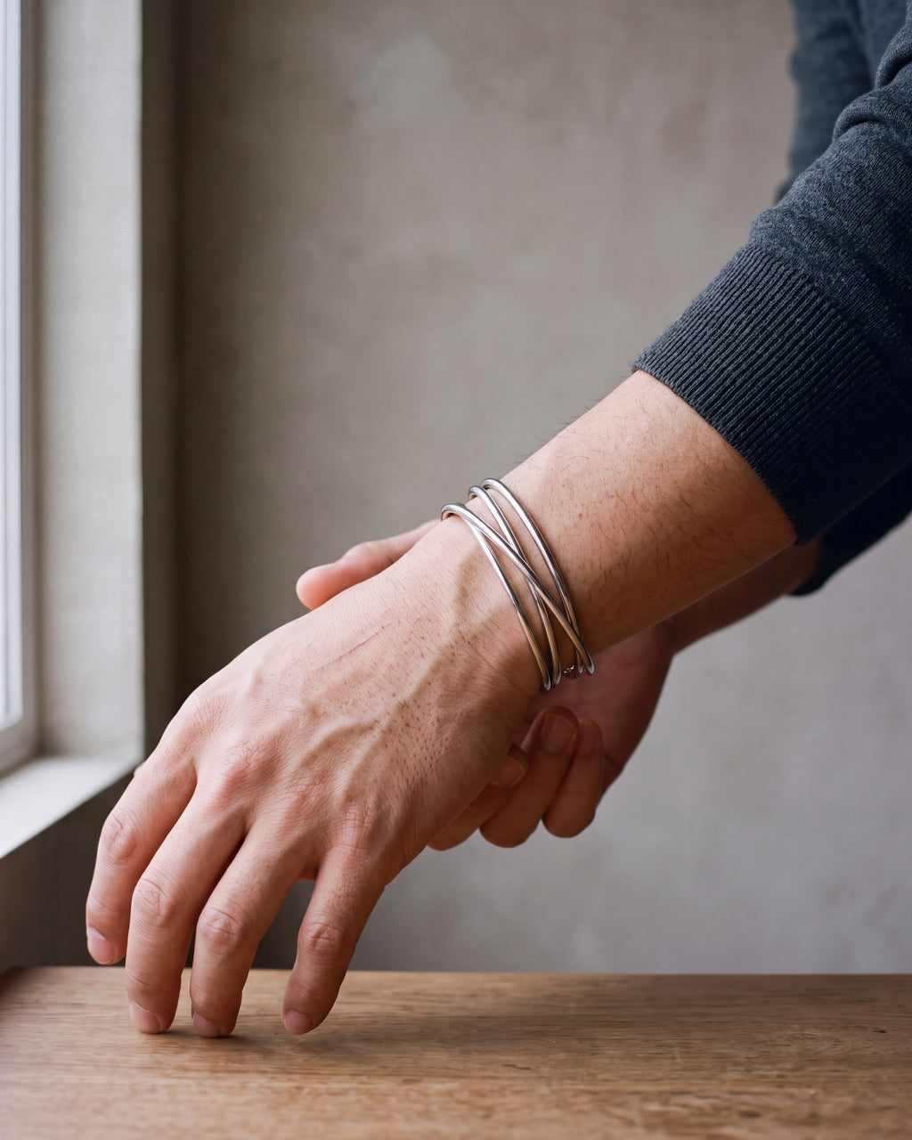 Close-up of the silver-tone Atlas multi-line open cuff bracelet worn by a man, shown at true size