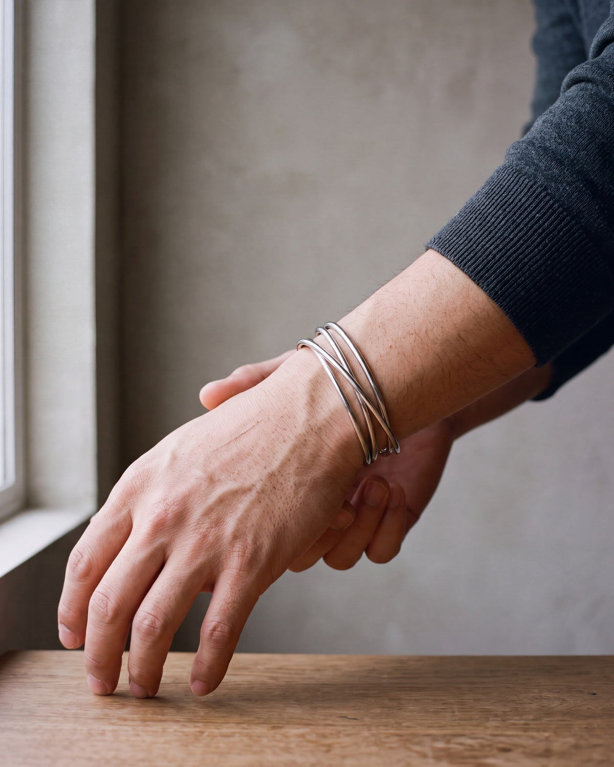 Close-up of the silver-tone Atlas multi-line open cuff bracelet worn by a man, shown at true size