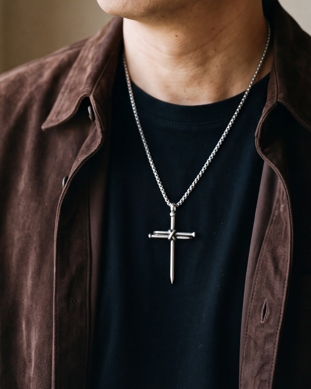 Close-up of the Atlas nail cross pendant on a man's chest