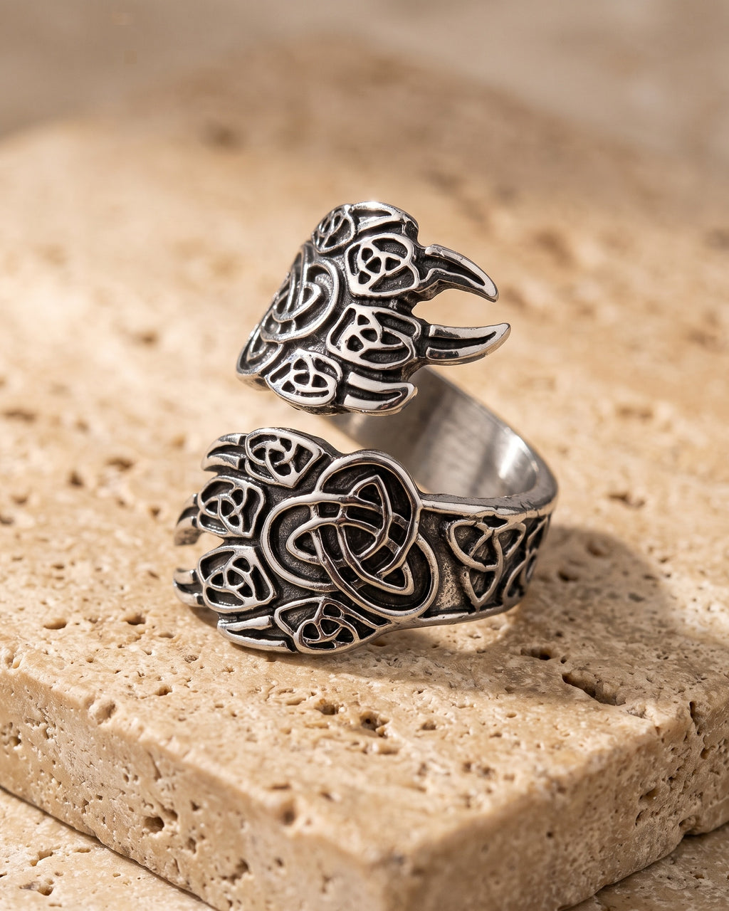 Entire Atlas Norse claw adjustable ring in silver-tone steel, lying flat on warm stone