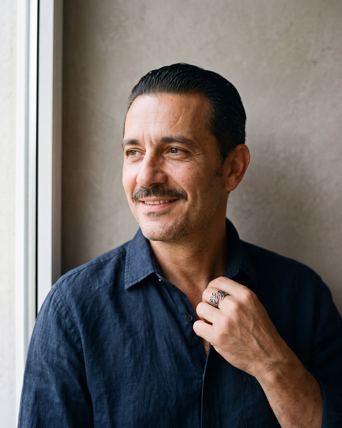 Man in a navy linen shirt wearing the Atlas Norse claw adjustable ring in silver-tone steel