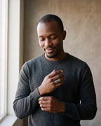 Man in a charcoal knit sweater by a window wearing the Atlas Norse claw adjustable ring in silver-tone steel
