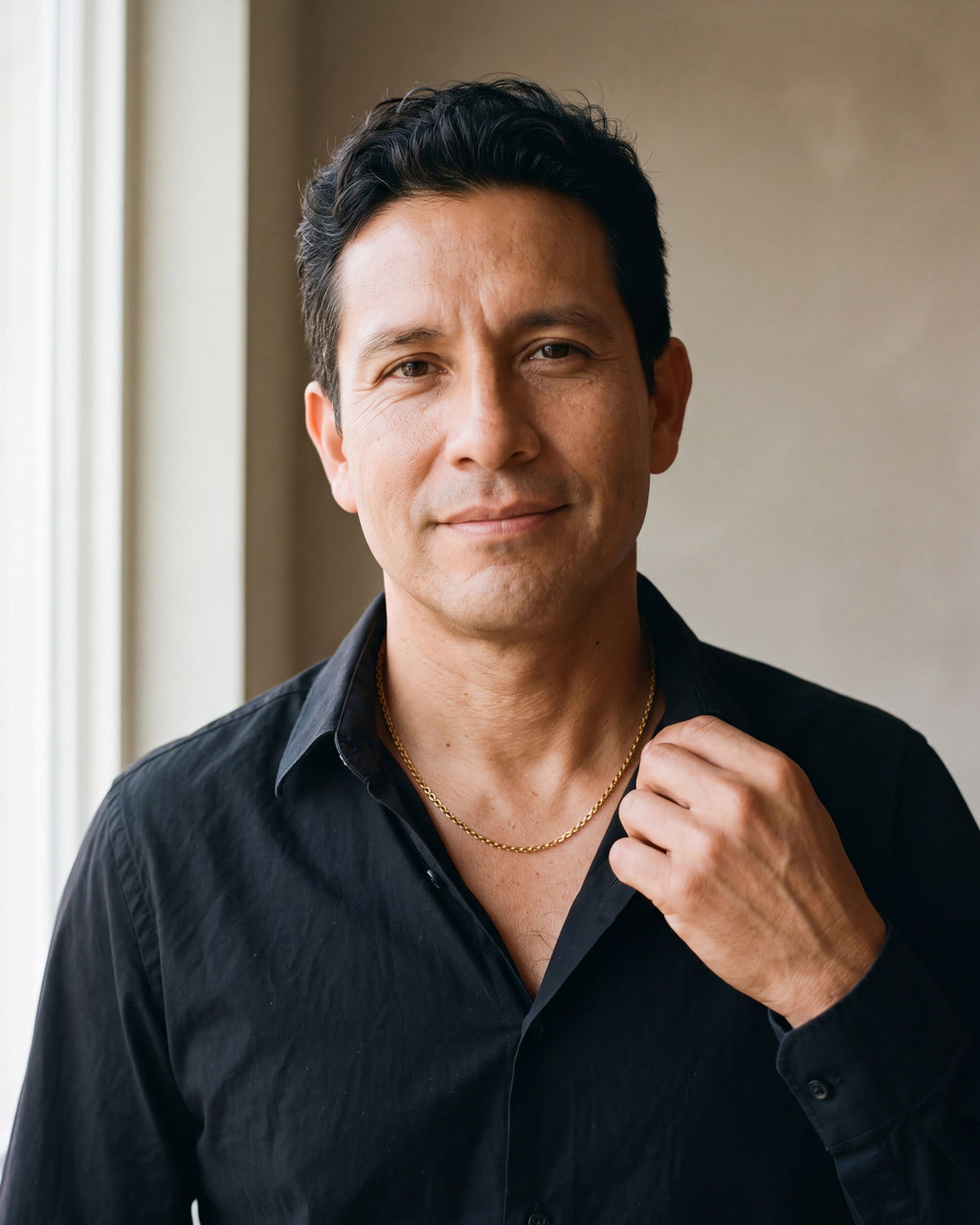 Man in an open-collar black shirt wearing the gold-tone Atlas O-link chain